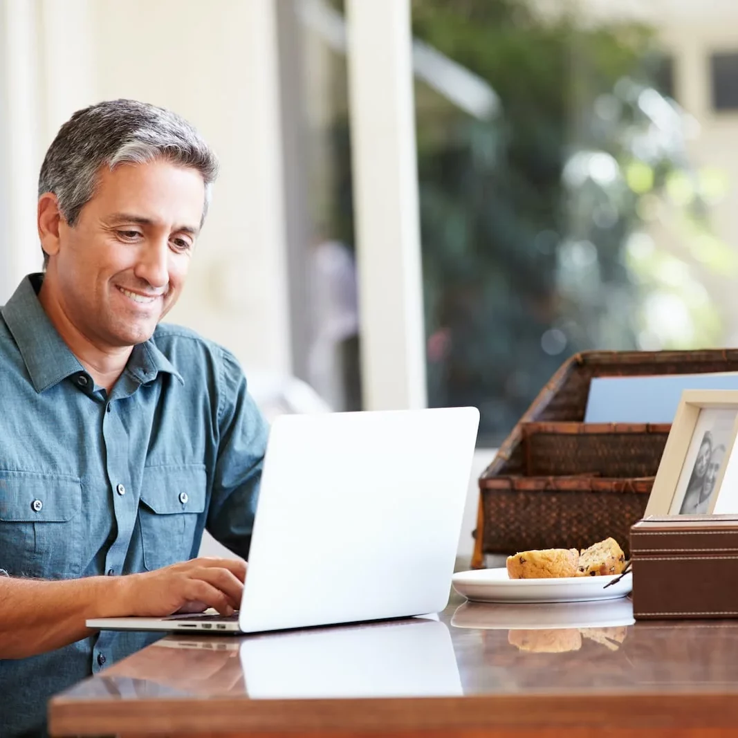 man at laptop smiling at desk